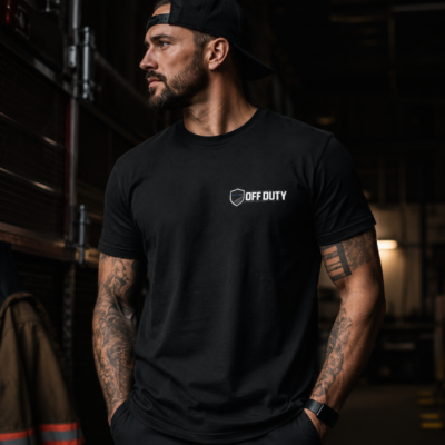 Man wearing olive green Off Duty logo t-shirt in a rugged gym setting with American flag background